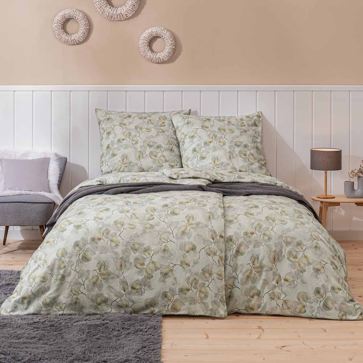 Bettwäsche Molveno mit zarten Ginkgo-Blättern und feinen Zweigen in soften Grün-, Gelb- und Grautönen auf blassgrünen Grund auf Bett im Schlafzimmer